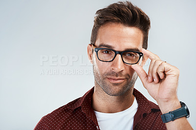 Buy stock photo Portrait of a cheerful young man wearing glasses and smiling brightly while standing against a grey background