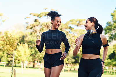 Buy stock photo Cropped shot of two attractive young women running next to each other in the park during the day