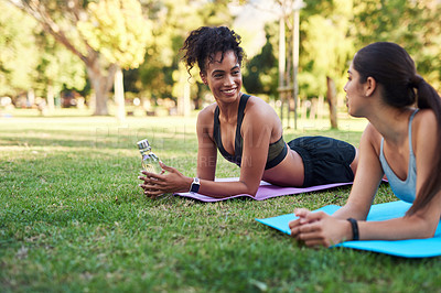 Buy stock photo Cropped shot of two attractive young women stretching next to each other in the park during the day