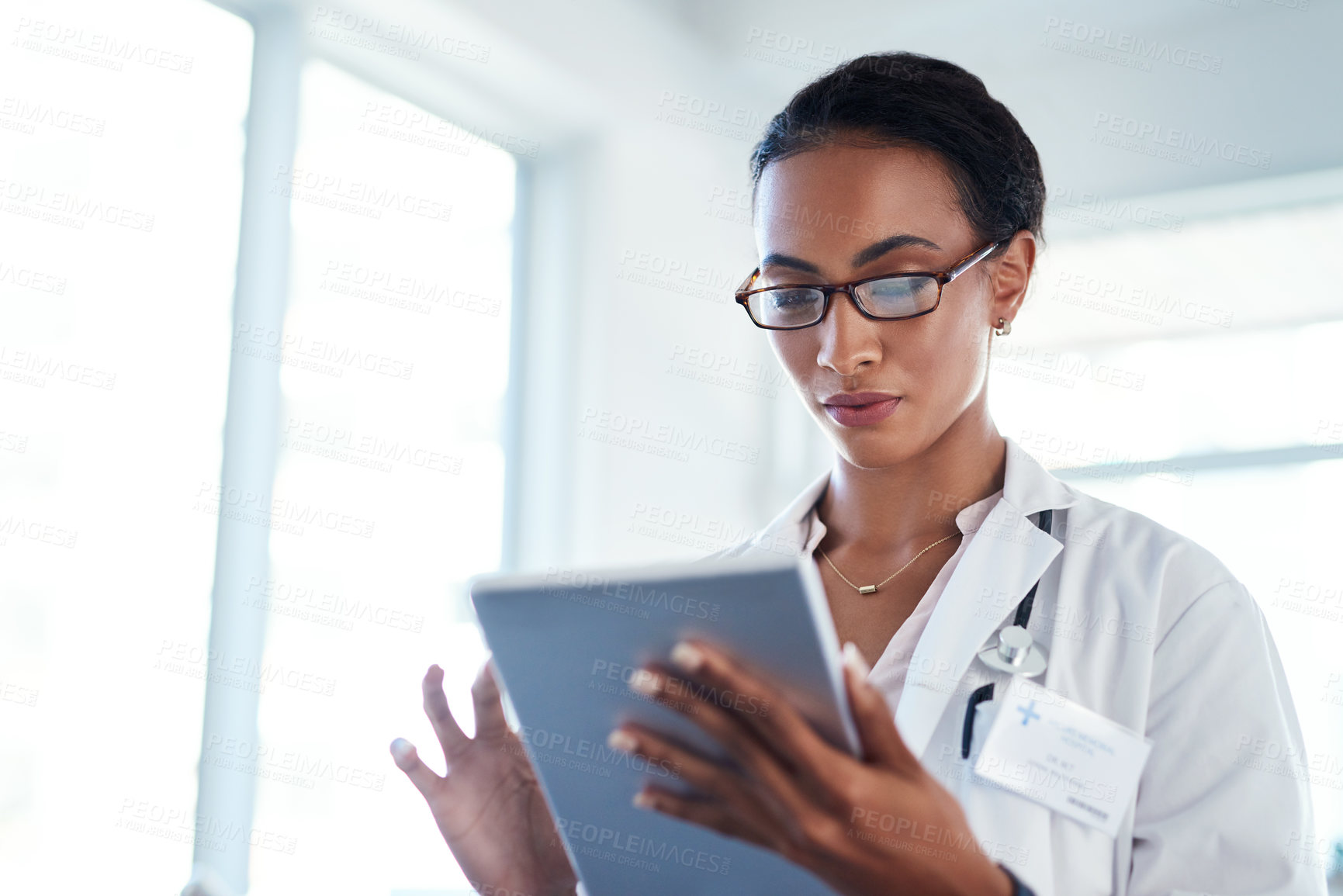 Buy stock photo Shot of a young doctor using a digital tablet in her consulting room