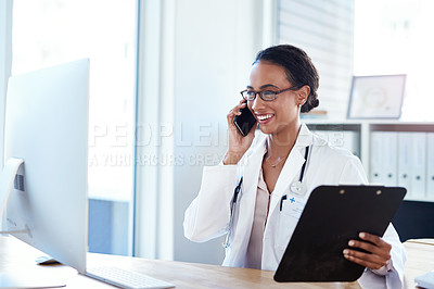 Buy stock photo Shot of a young doctor using a smartphone and computer in her consulting room
