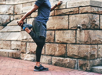 Buy stock photo Shot of an unrecognizable sportsman stretching and warming before exercising outdoors in the city