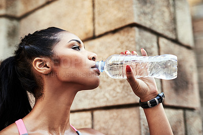 Buy stock photo Shot of an attractive young sportswoman drinking water from a bottle while exercising outdoors