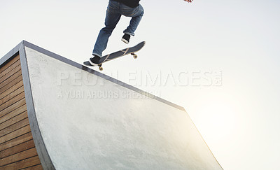 Buy stock photo Shot of an unrecognizable man doing tricks on his skateboard at a skate park