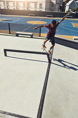 Buy stock photo Full length shot of a skateboarder doing tricks on a rail at a skate park