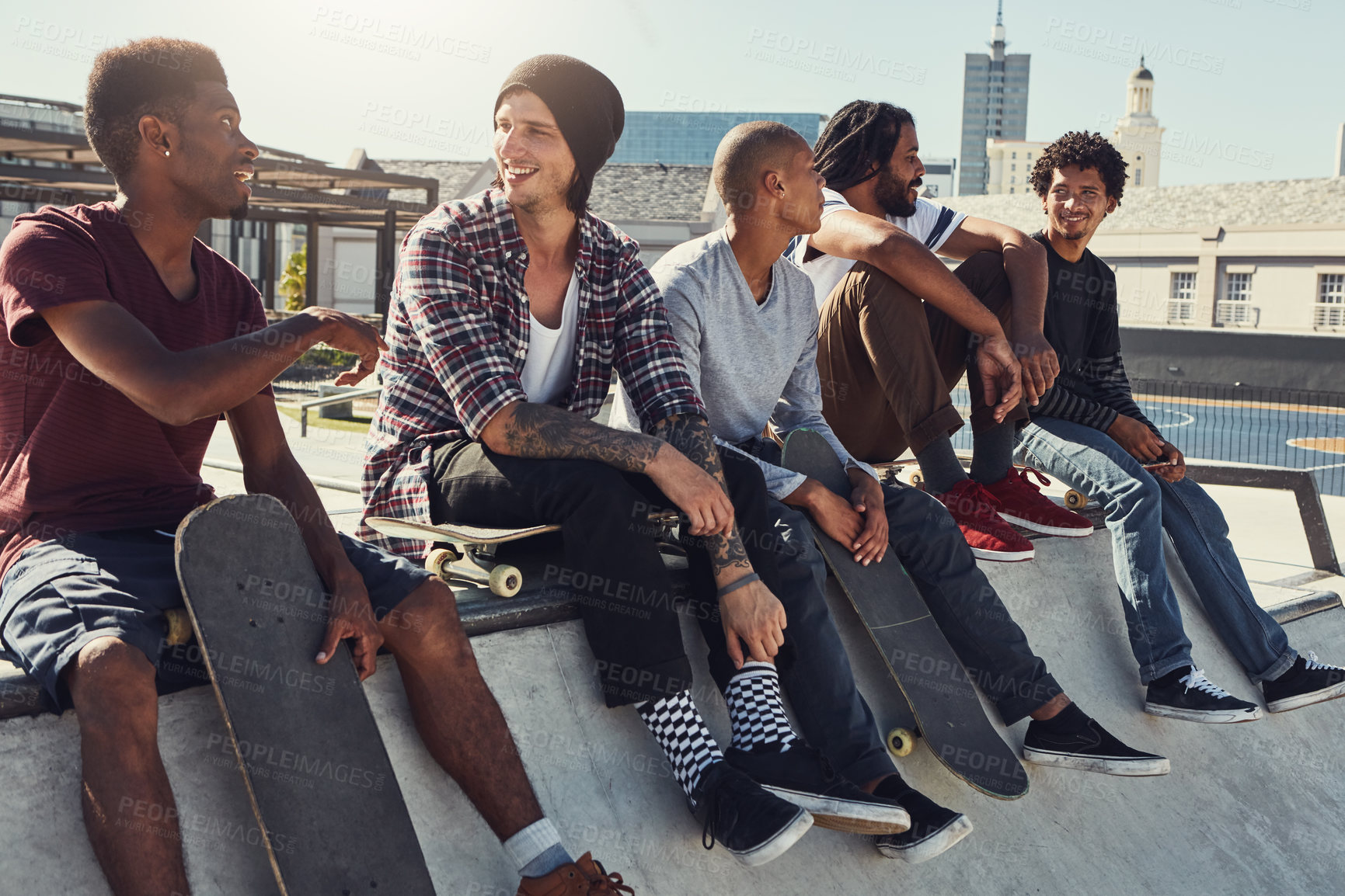 Buy stock photo Shot of a group of friends sitting together on a ramp at a skatepark