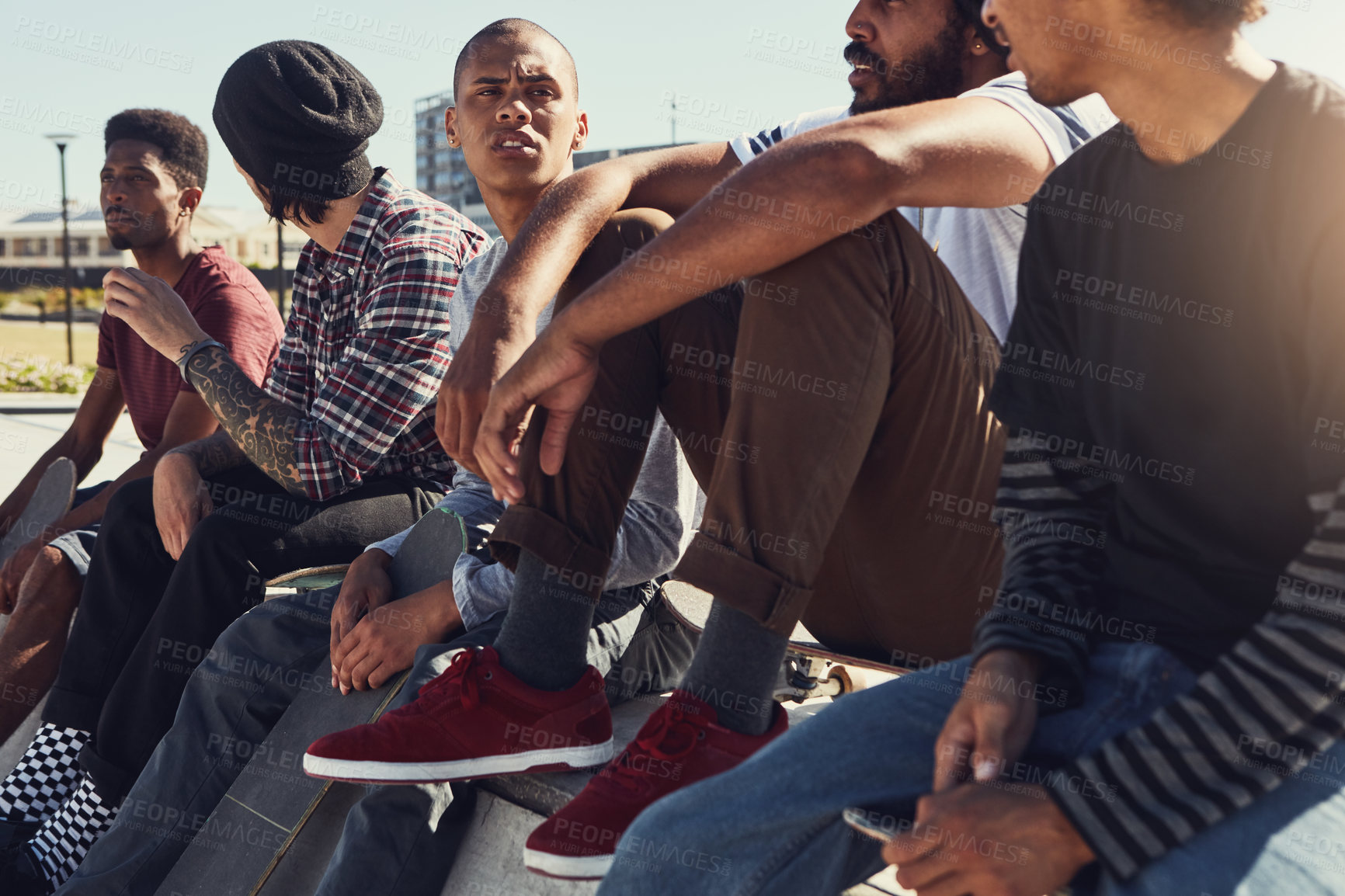 Buy stock photo Shot of a group of friends sitting together on a ramp at a skatepark