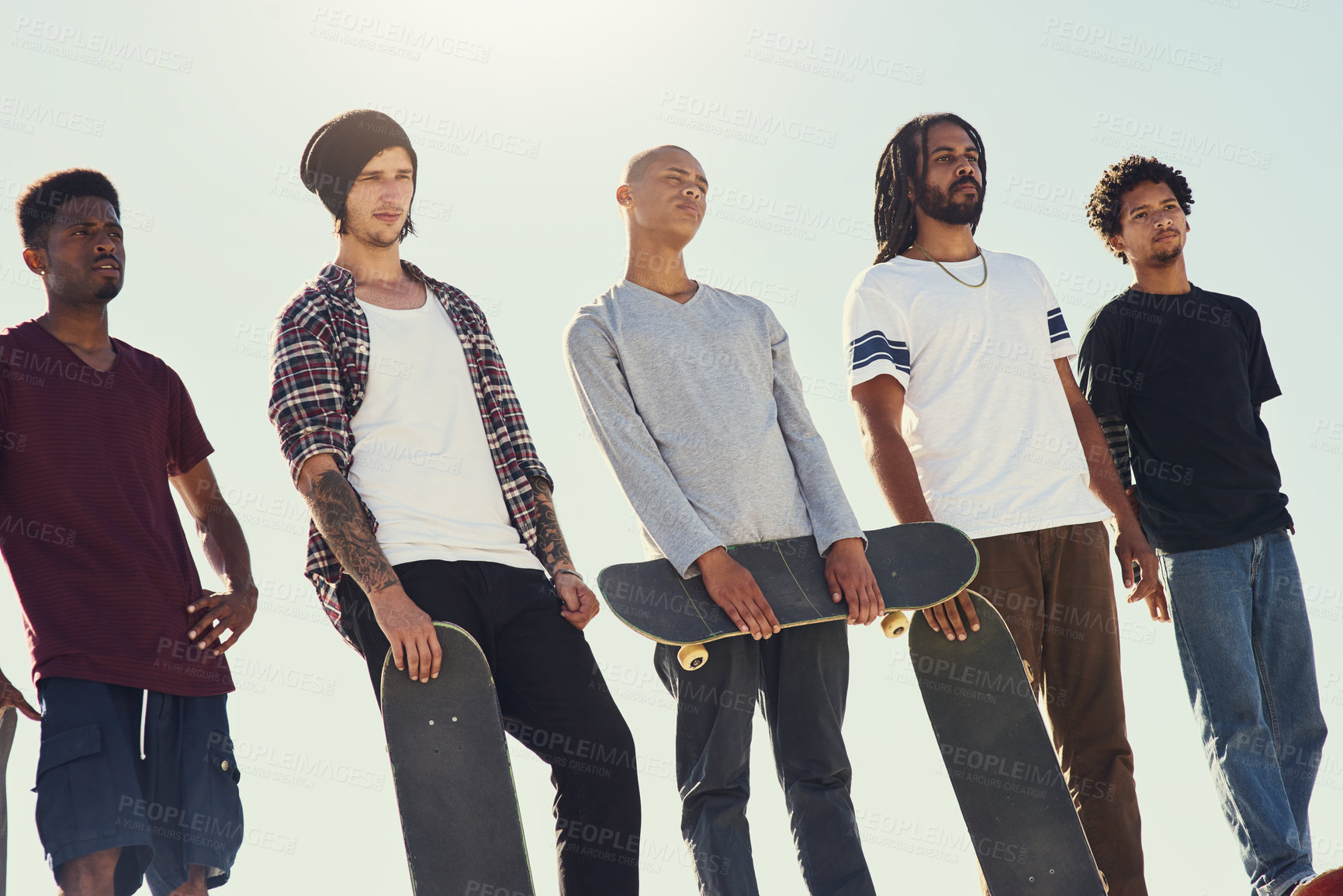 Buy stock photo Shot of a group of friends standing together on a ramp at a skatepark