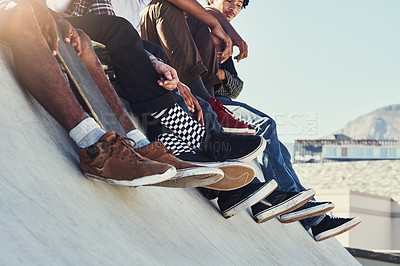 Buy stock photo Shot of a group of unrecognizable skaters sitting together on a ramp at a skatepark