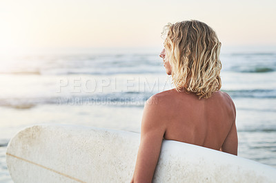 Buy stock photo Rearview shot of a young surfer looking at the ocean waves before going surfing at the beach