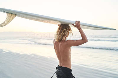 Buy stock photo Rearview shot of a young surfer carrying his surfboard over his head at the beach