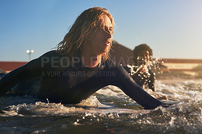 Buy stock photo Shot of two young surfers surfing together in the ocean