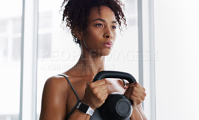 Buy stock photo Shot of a young woman working out with kettlebells in a gym