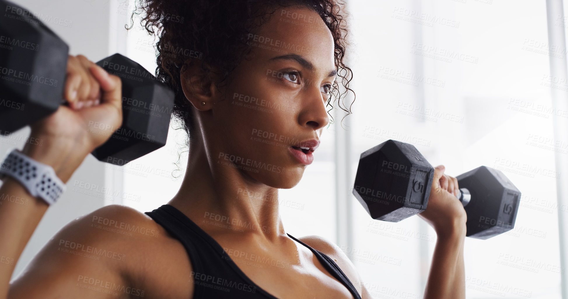 Buy stock photo Shot of a young woman working out with dumbbells in a gym