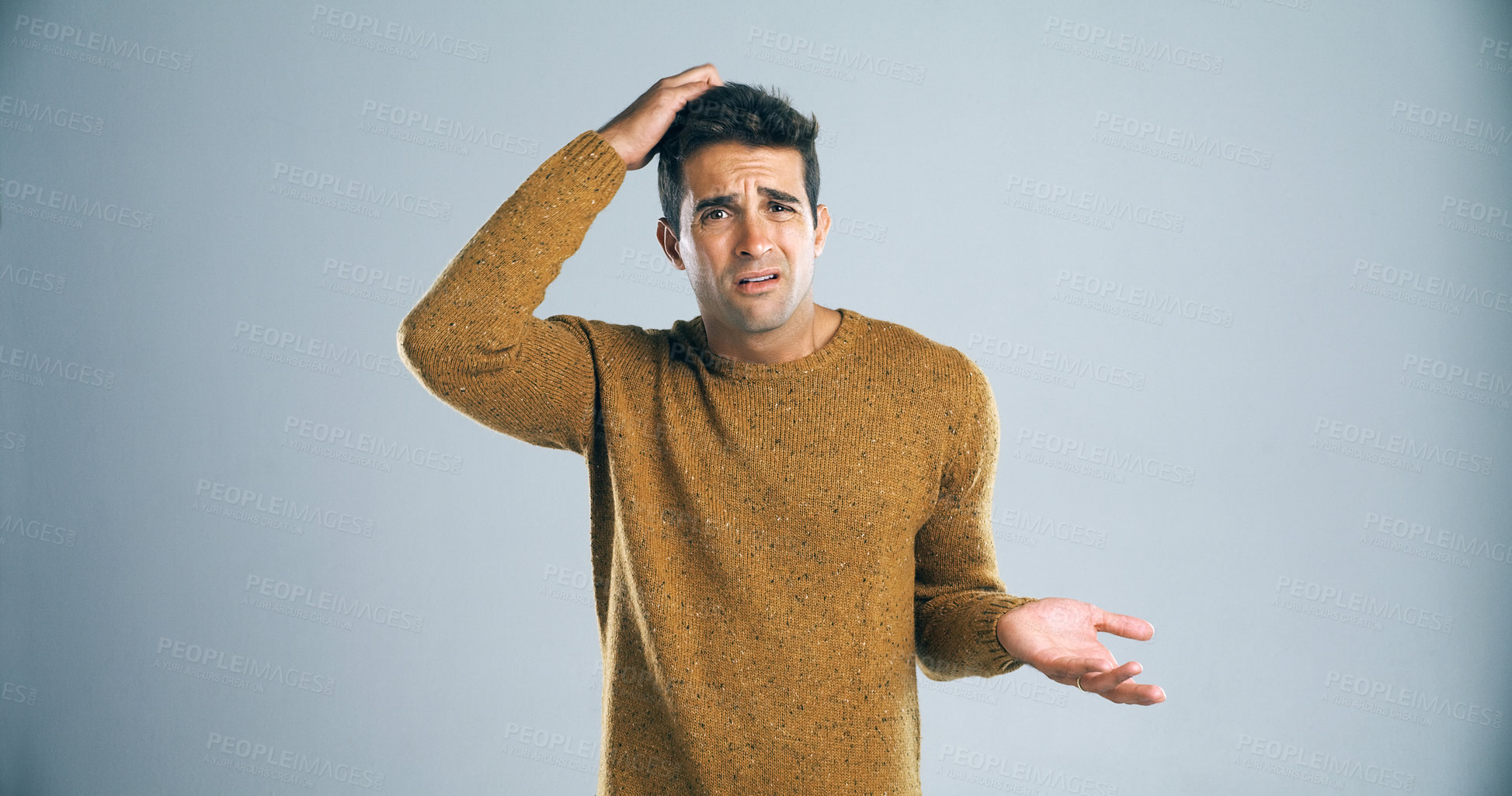 Buy stock photo Studio shot of a handsome young man scratching his head in confusion against a gray background
