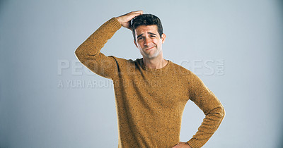 Buy stock photo Studio shot of a handsome young man scratching his head in confusion against a gray background