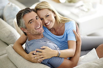 Buy stock photo Cropped portrait of an affectionate mature couple laughing while relaxing at home on the sofa