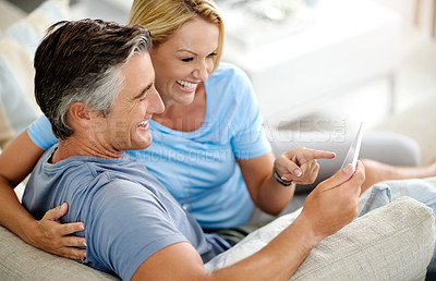 Buy stock photo Lounge, relax and couple with tablet, laughing and watch of movie, pointing and subscription for entertainment. House, man and woman with app, streaming and happy in living room, smile and bonding