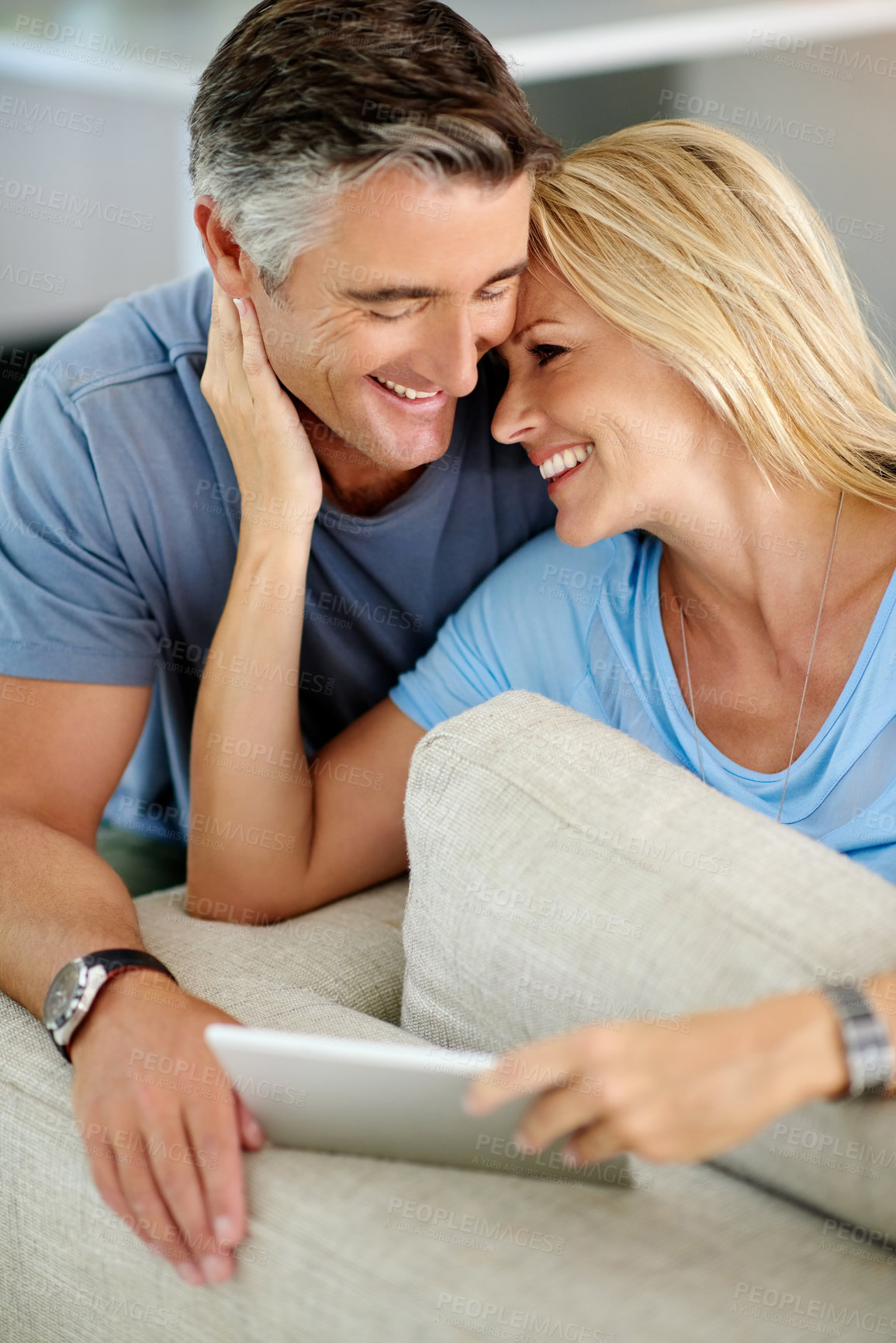 Buy stock photo Lounge, bonding and couple with tablet, affection and watch of movie, romance and subscription for entertainment. House, man and woman with app, streaming and happy in living room, break and smile