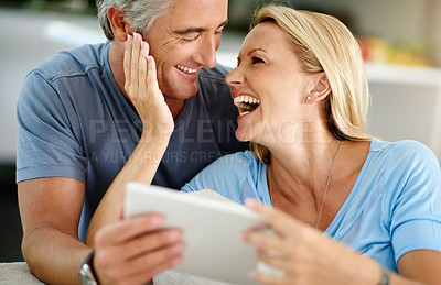 Buy stock photo Cropped shot of an affectionate mature couple laughing while using a digital tablet on the sofa at home
