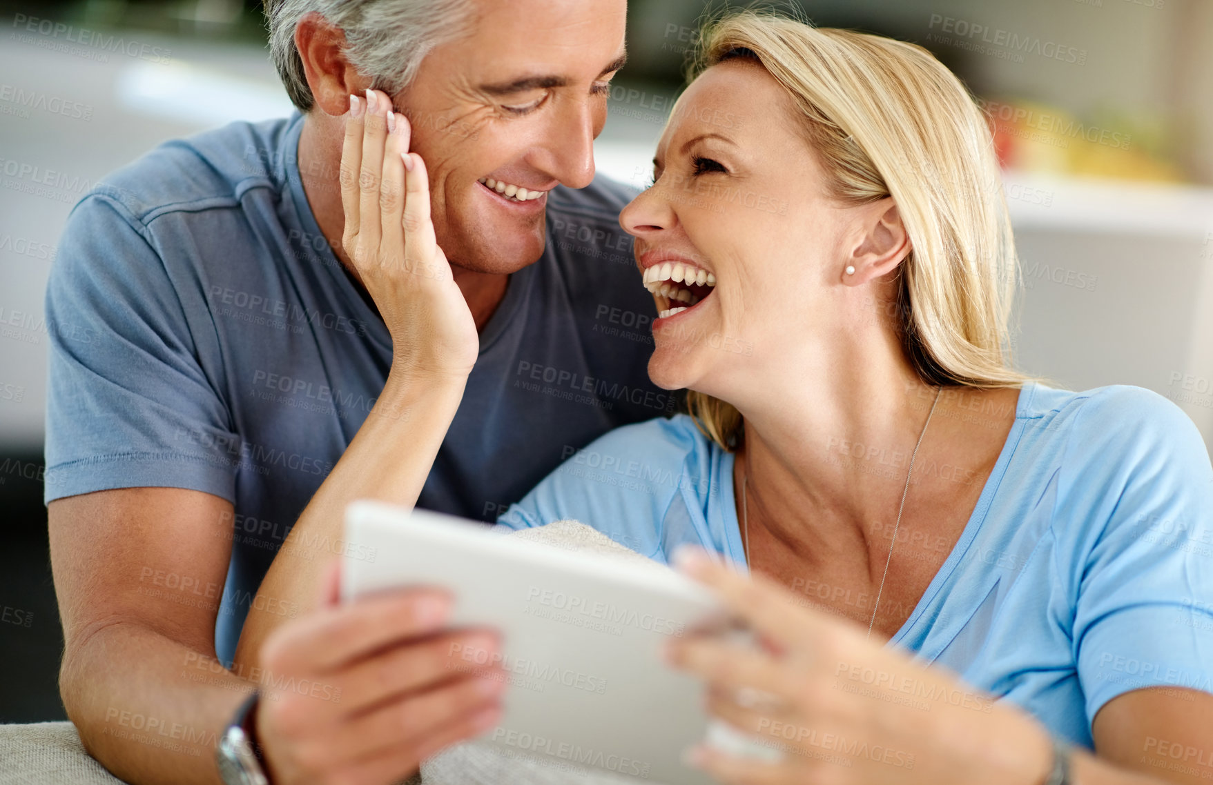 Buy stock photo Cropped shot of an affectionate mature couple laughing while using a digital tablet on the sofa at home