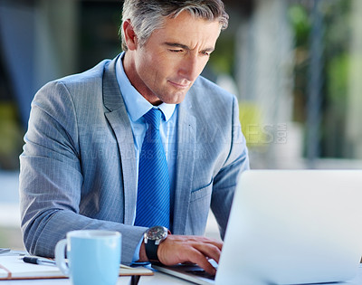 Buy stock photo Cropped shot of a handsome mature businessman working on a laptop outdoors