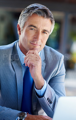 Buy stock photo Cropped portrait of a handsome mature businessman looking thoughtful while working on a laptop outdoors