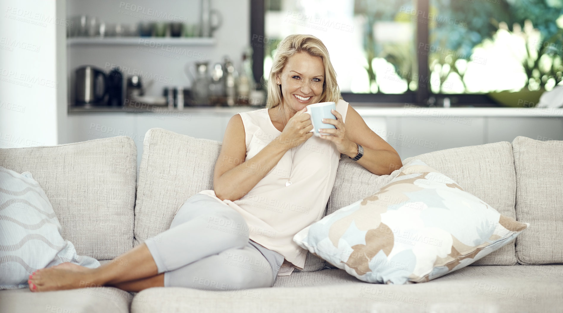 Buy stock photo Mature, woman and smile with tea in home for relax, wellness and weekend break with confidence on sofa. Person, happy and drinking coffee on couch in lounge with pride, hot beverage and resting