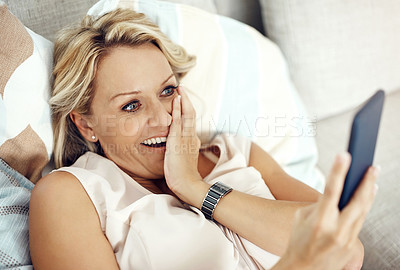Buy stock photo Cropped shot of an attractive mature woman looking surprised while reading a text message at home
