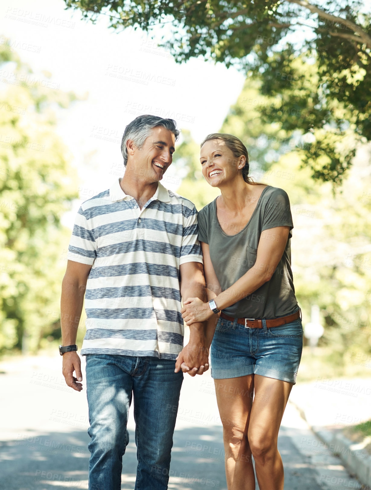 Buy stock photo Laugh, holding hands and happy couple in road walking for bonding, relationship and love outdoors. Nature, marriage and mature man and woman for romance, affection and relax on weekend together