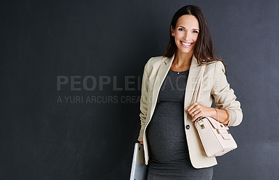 Buy stock photo Studio portrait of a young pregnant businesswoman standing against a black background