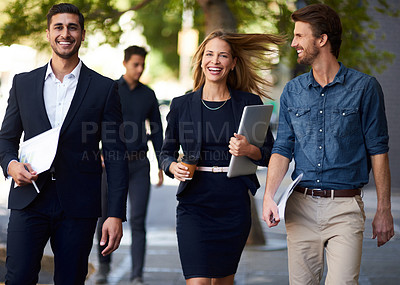 Buy stock photo Cropped shot of a group of corporate colleagues walking down the street on their way to work