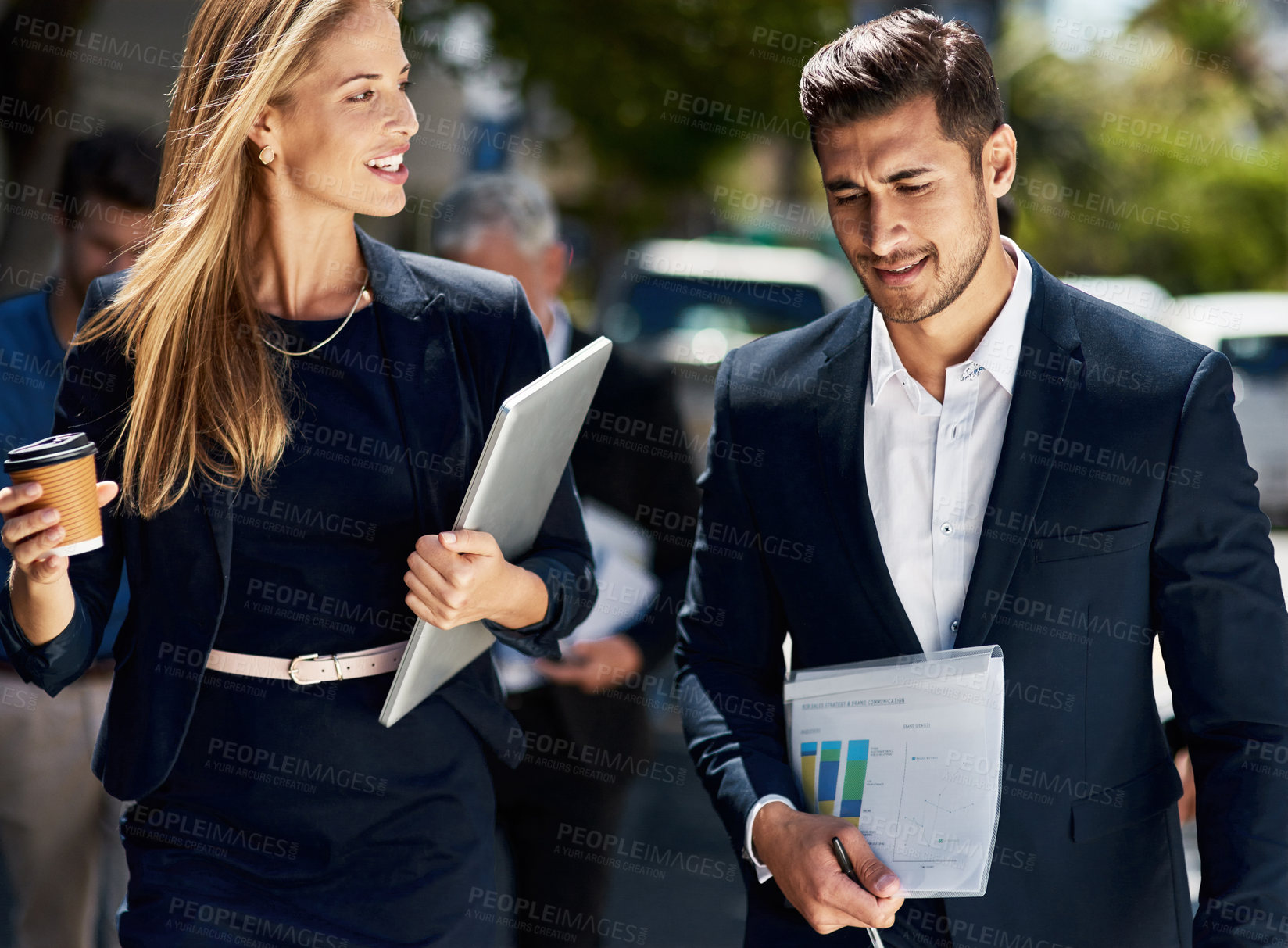 Buy stock photo Cropped shot of two corporate colleagues having a discussion while walking down the street on their way to work