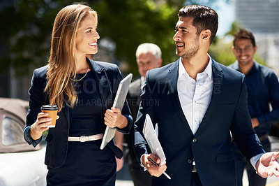 Buy stock photo Cropped shot of two corporate colleagues having a discussion while walking down the street on their way to work