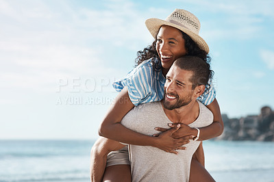 Buy stock photo Shot of a young man piggybacking his girlfriend at the beach
