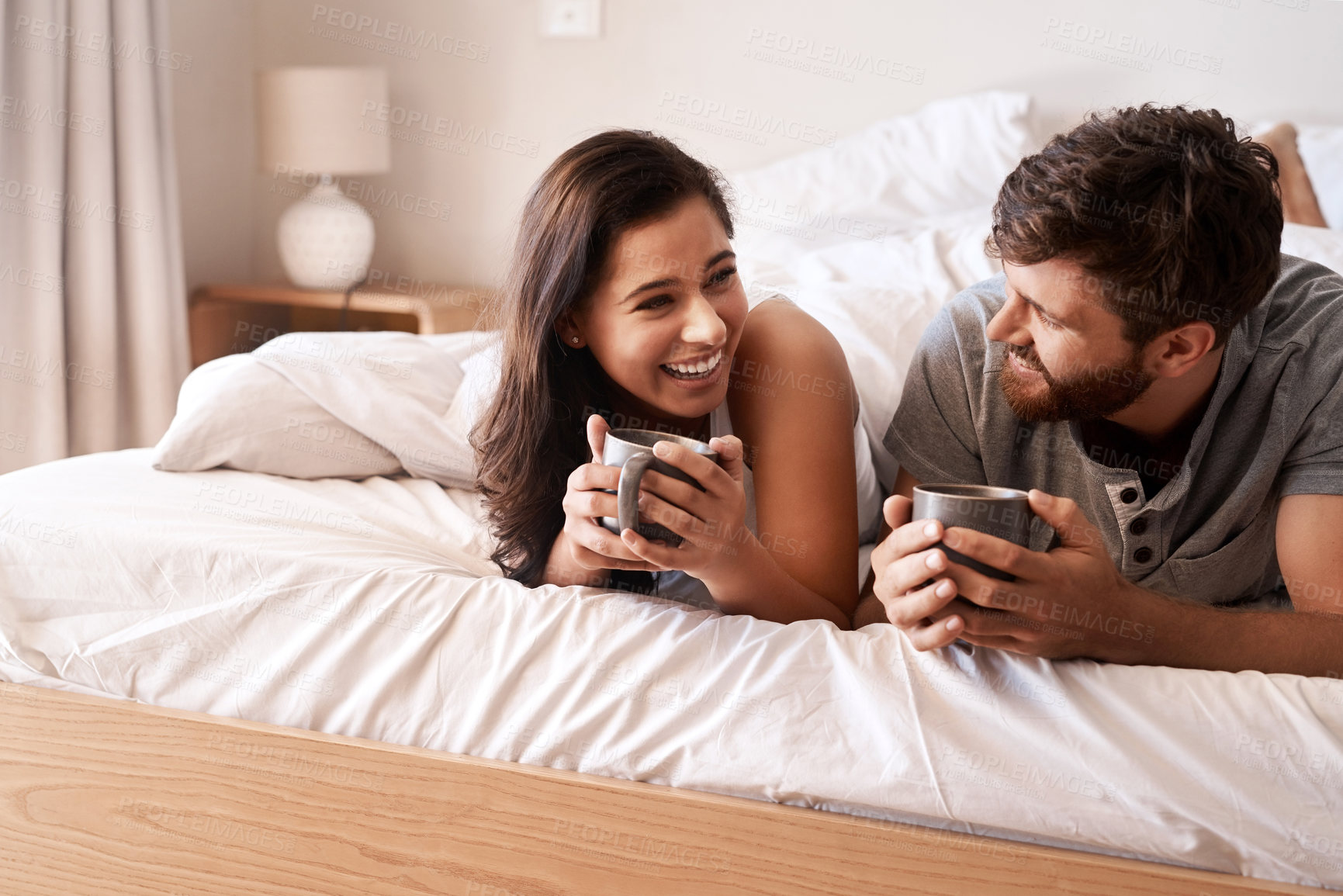 Buy stock photo Bed, coffee cup and happy couple bonding, relax and enjoy morning latte, home drinks or hydration beverage. Comedy, funny and romantic man, woman or people with tea, love and laughing at bedroom joke