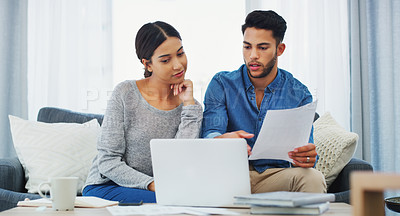 Buy stock photo Cropped shot of a happy young couple sitting on the sofa while going through paperwork in their lounge