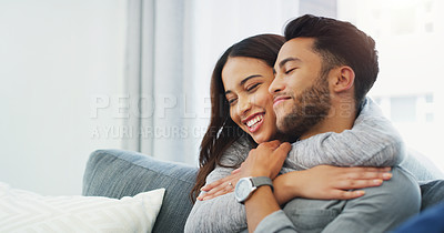 Buy stock photo Cropped shot of an affectionate young couple cuddling with each other while in their living room during the day