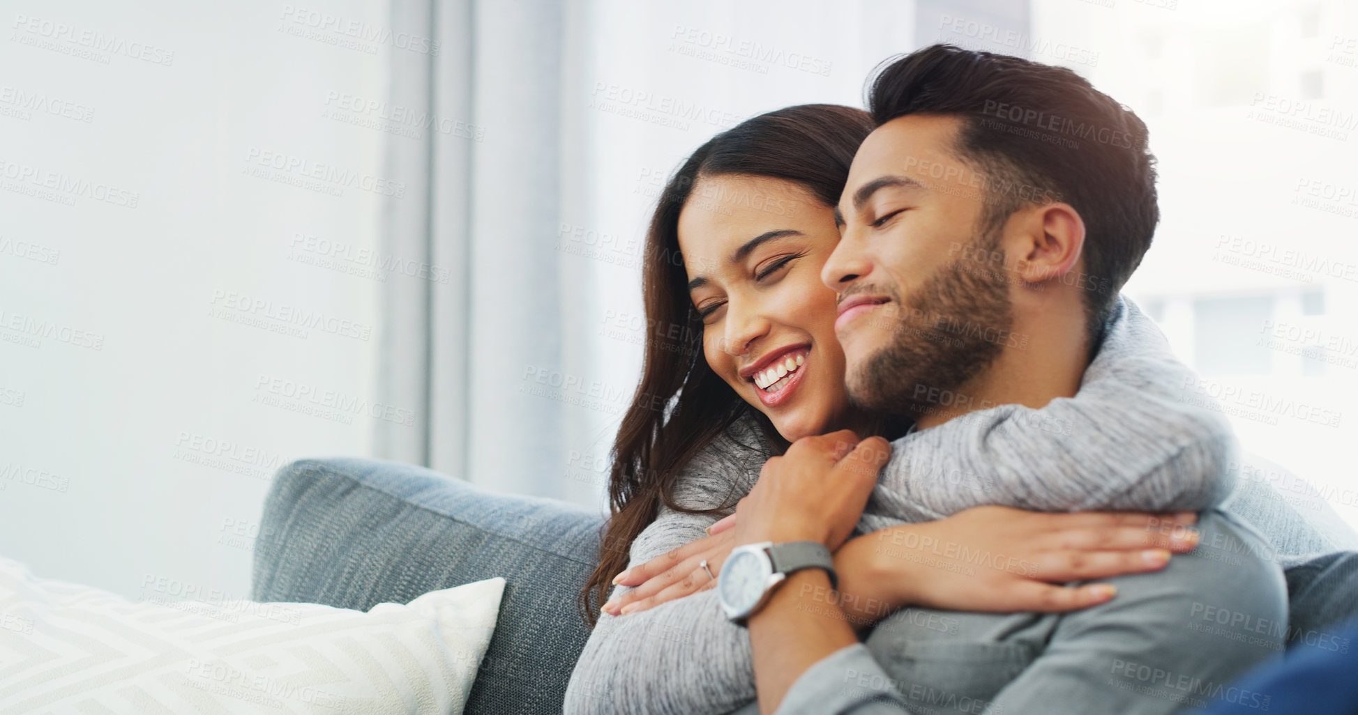 Buy stock photo Cropped shot of an affectionate young couple cuddling with each other while in their living room during the day