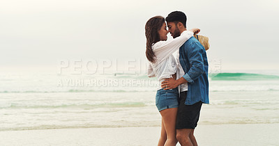 Buy stock photo Cropped shot of an affectionate young couple holding each other closely while standing on the beach during the day