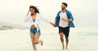 Buy stock photo Full length shot of an affectionate young couple holding hands and running through the water at the beach