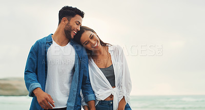 Buy stock photo Cropped shot of an affectionate young couple holding hands and walking along the beach during the day