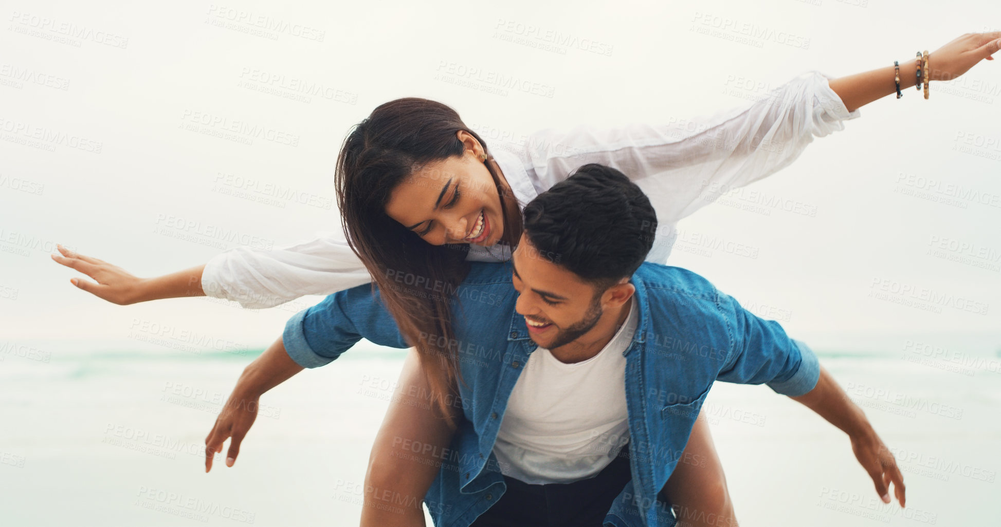 Buy stock photo Cropped shot of a playful young couple enjoying their time together on the beach during the day