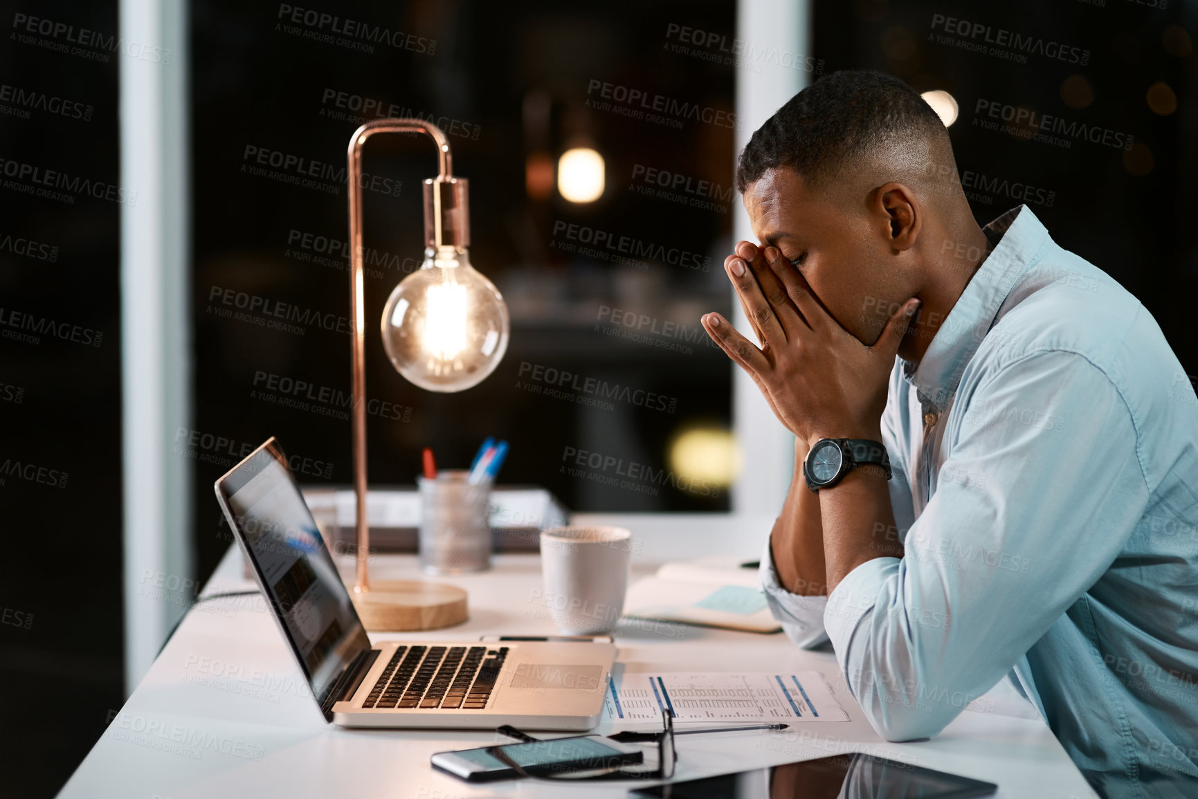 Buy stock photo Shot of a handsome young businessman feeling stressed out while working late in his office