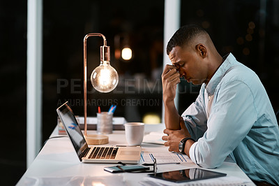 Buy stock photo Shot of a handsome young businessman feeling stressed out while working late in his office
