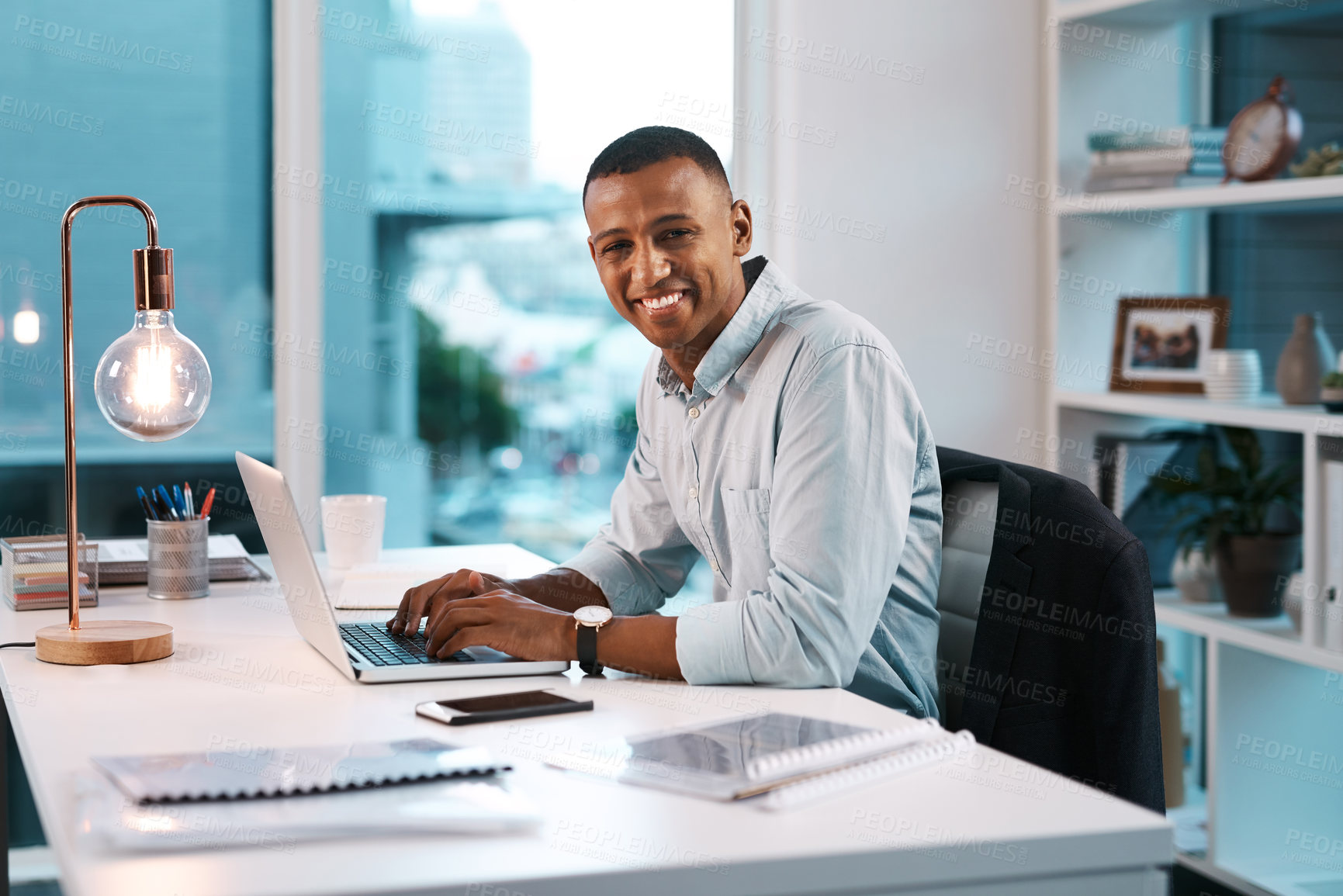 Buy stock photo Portrait of a handsome young businessman working on his laptop during a late night shift at work