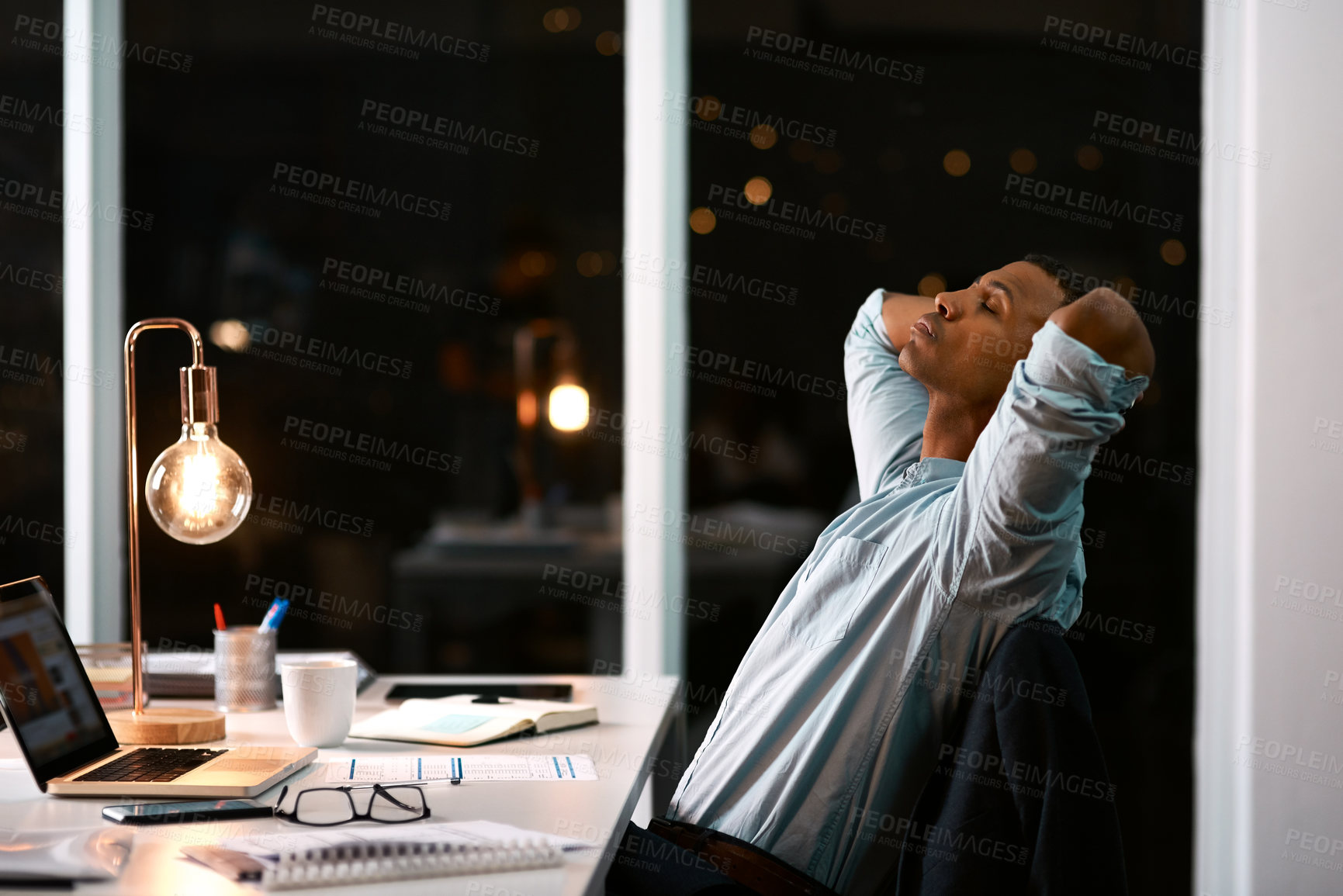 Buy stock photo Shot of a handsome young businessman feeling stressed out while working late in his office