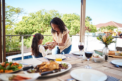 Buy stock photo Shot of a beautiful young mother passing a bowl of salad to her daughter while feasting outdoors