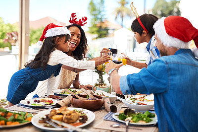 Buy stock photo Shot of a beautiful young family sharing a toast while enjoying Christmas lunch together outdoors