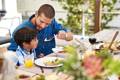 Buy stock photo Shot of a father feeding his young son while having a meal together outdoors
